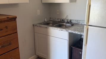 A kitchen with white cabinets, a granite countertop, a stainless steel sink, and a white refrigerator.