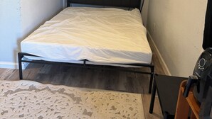Een slaapkamer met een bed, nachtkastje, stoel, klein tafeltje en twee potplanten.