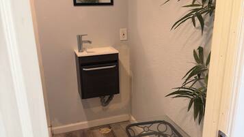 A bathroom with a sink, mirror, and a small table with a chair.