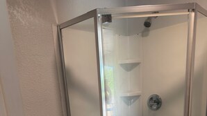Een badkamer met een douchecabine van glas, een toilet en een houten vloer.