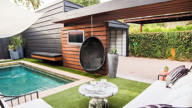 Un área de piscina moderna al aire libre con una zona de estar y una hamaca colgante.