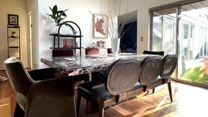 Un comedor moderno con una mesa de mármol, sillas negras y un amplio ventanal con vistas al exterior.