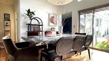 A modern dining area with a marble table, black chairs, and a large window providing a view of the outdoors.