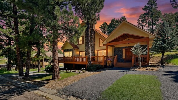 A two-story lodge with a stone facade, a wooden deck, and a well-maintained lawn. - Sunny Side Chalet (Ruidoso)