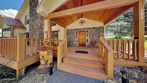 A wooden cabin with a stone facade, a porch with a wooden railing, and a Texan flag on the wall. - Sunny Side Chalet (Ruidoso)