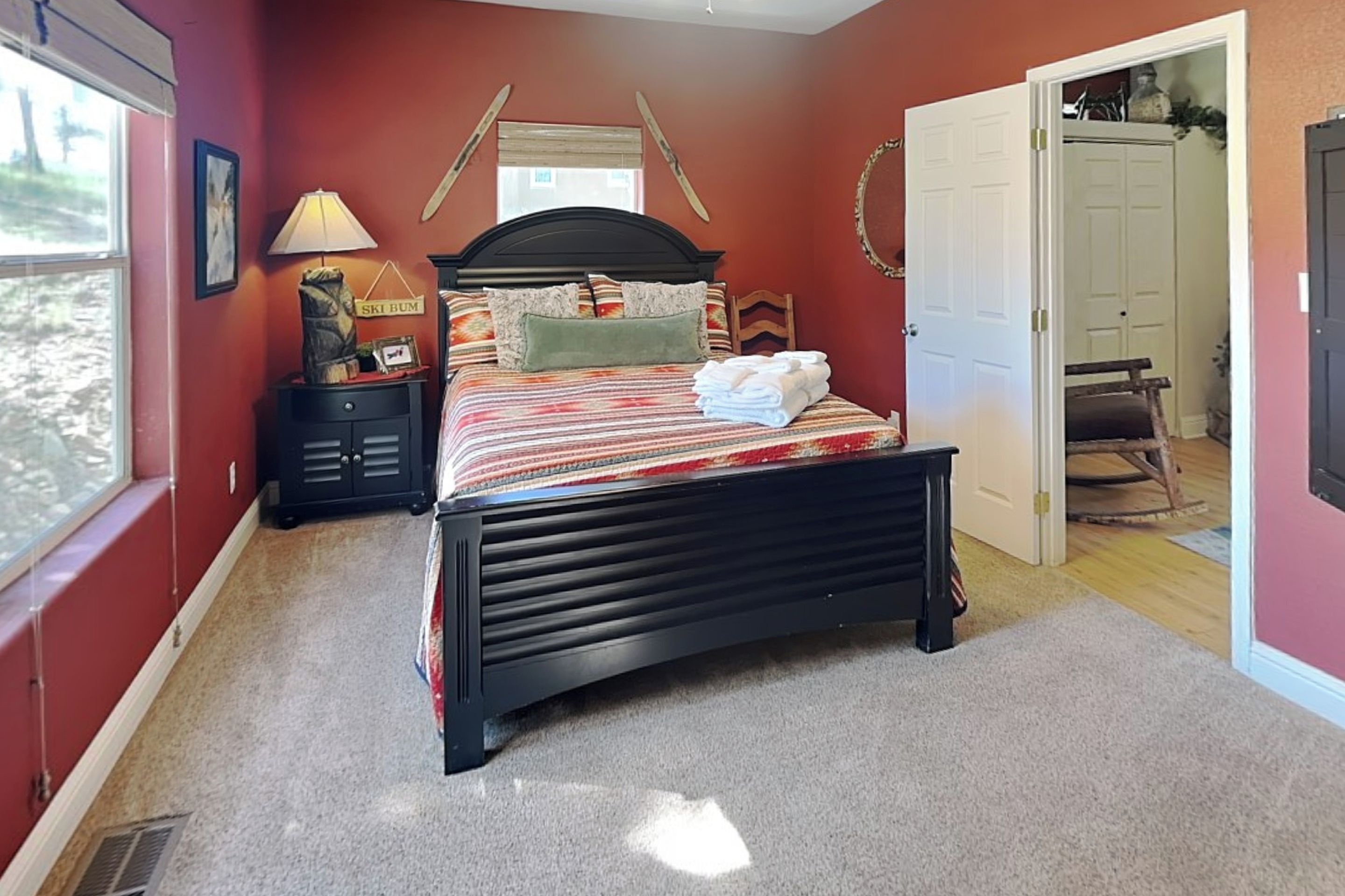 A bedroom with a bed, a nightstand, a lamp, a window, and a door.
