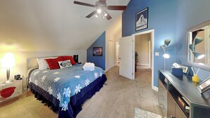 A bedroom with a bed, a ceiling fan, a nightstand, a lamp, a dresser, and a door leading to another room. - Sunny Side Chalet (Ruidoso)