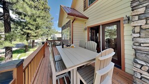 A deck with a table and chairs, overlooking a forested area. - Sunny Side Chalet (Ruidoso)