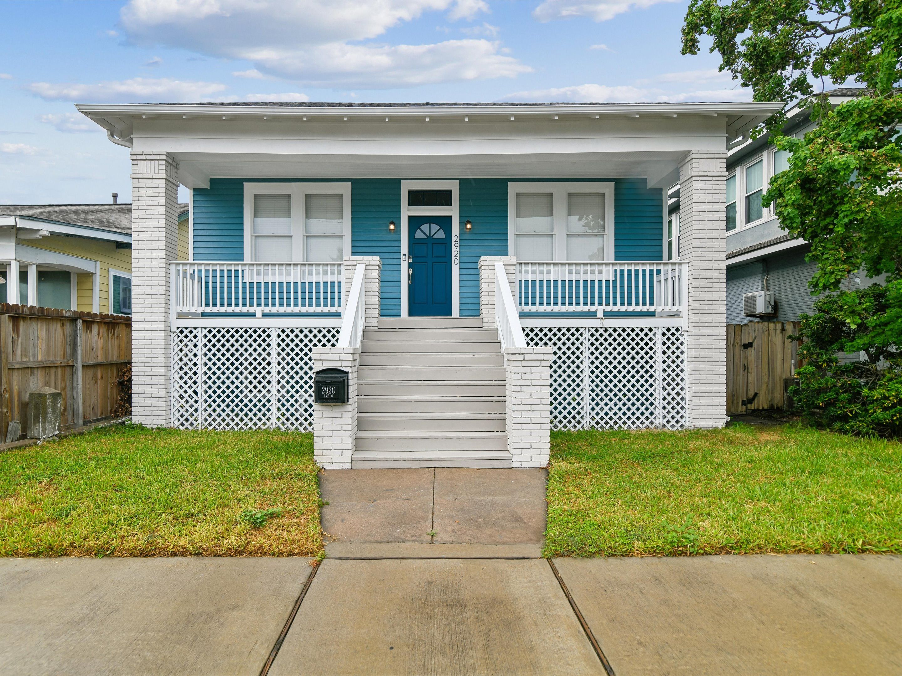 A two-story house with a front porch, a mailbox, and a number plate.