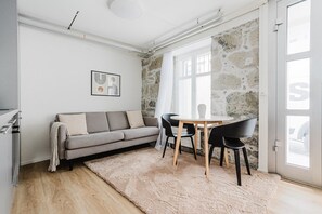 Ein modernes Wohnzimmer mit einem grauen Sofa, einem runden Tisch und schwarzen Stühlen.