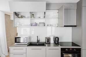 A modern kitchen with a built-in microwave, coffee maker, and oven. - Bright 1.5-room apartment in Kreis 6, roof terrace, near ETH (Zürich)