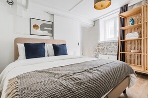 A bedroom with a bed, a headboard, a bedside table, a wall-mounted shelf, and a window. - Bright 1.5-room apartment in Kreis 6, roof terrace, near ETH (Zürich)