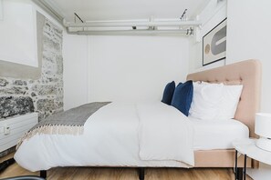 Ein Schlafzimmer mit einem Bett, einem Nachttisch, einer Lampe und einer Steinwand.