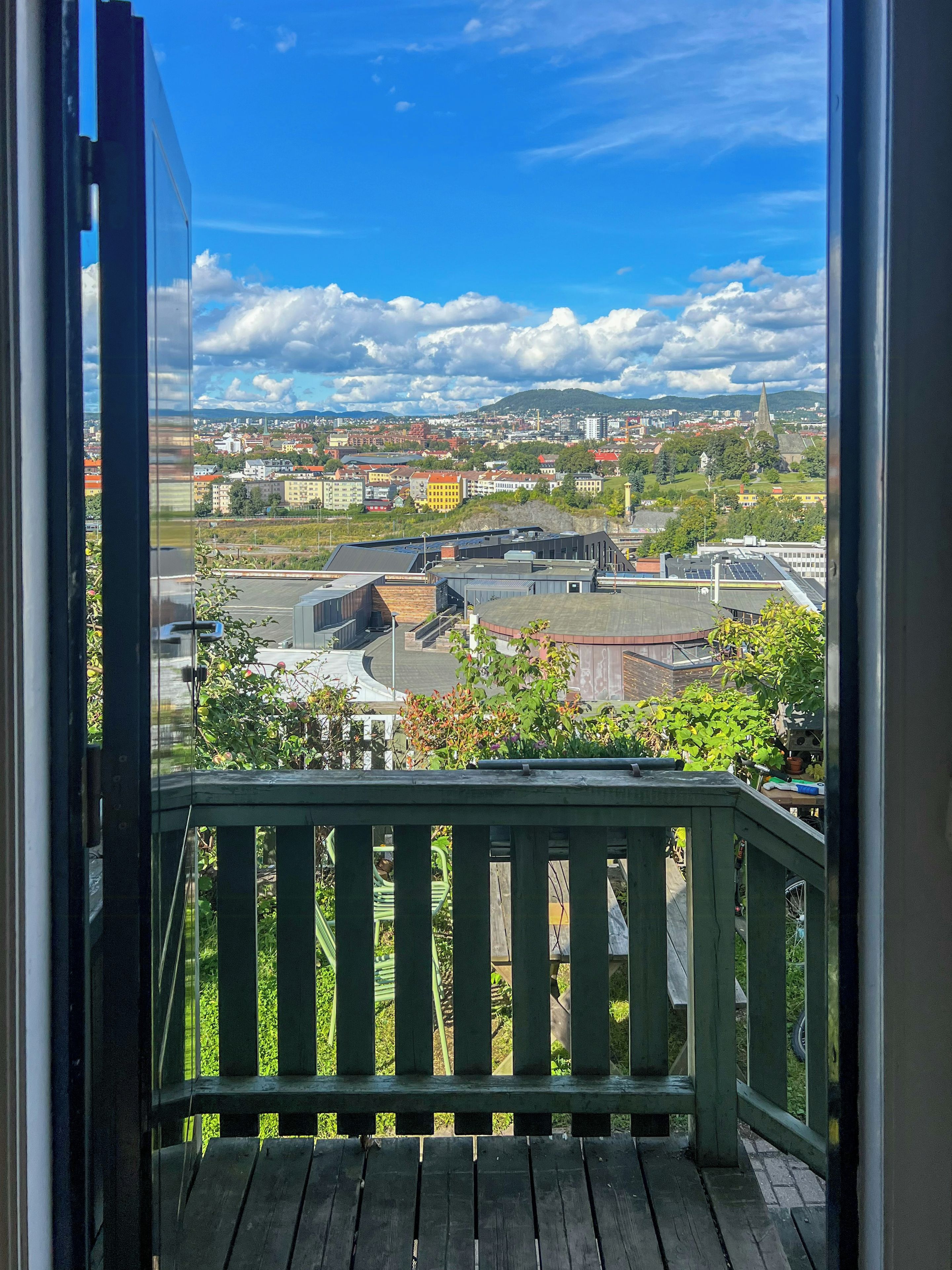 A balcony with a view of a cityscape, including buildings and a church steeple.