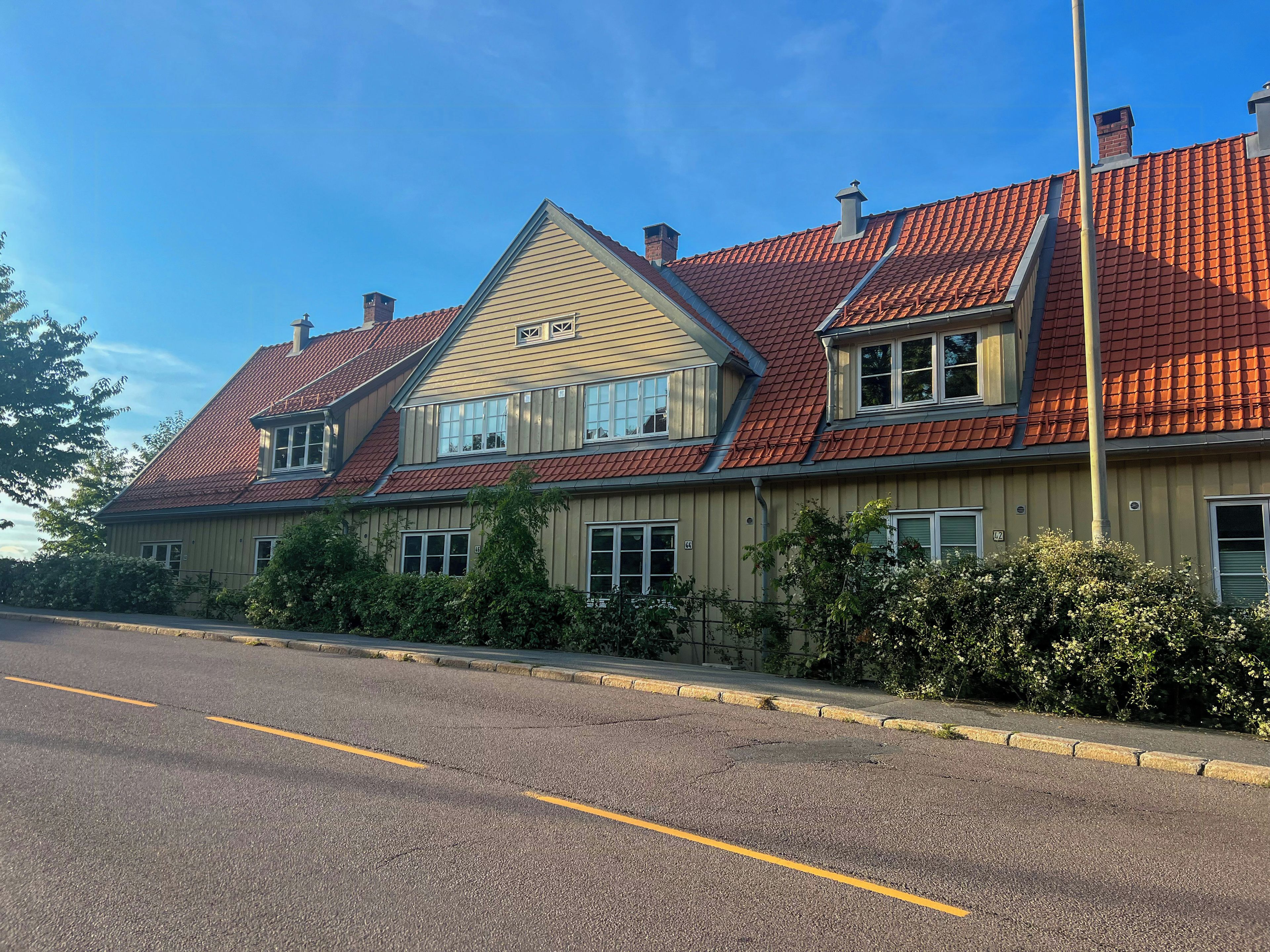 A two-story building with a red-tiled roof, a chimney, and a window with shutters.