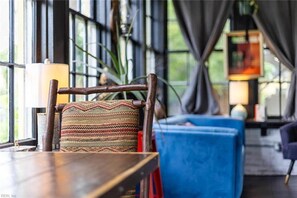 Una habitación con una silla de madera, un sofá azul y una lámpara.