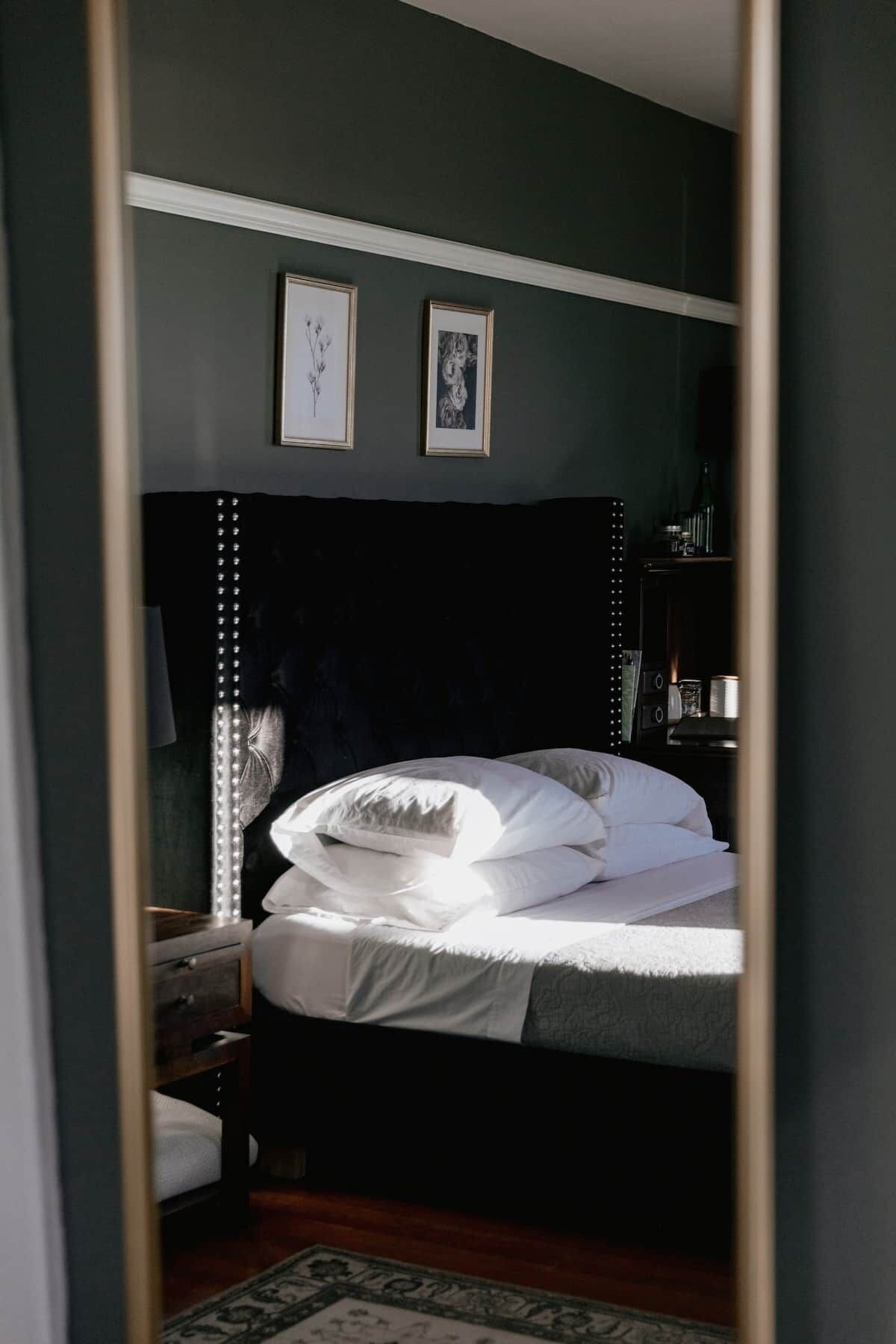 A bedroom with a bed, a nightstand, a dresser, and two framed pictures on the wall.