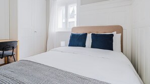 Quarto com uma cama, escrivaninha e janela.
