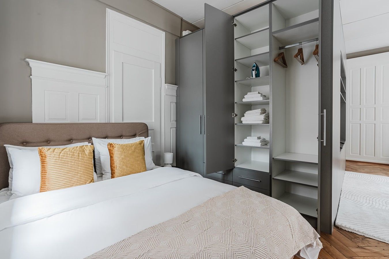 Une chambre à coucher avec un lit, une armoire et un placard où sont suspendus des vêtements.