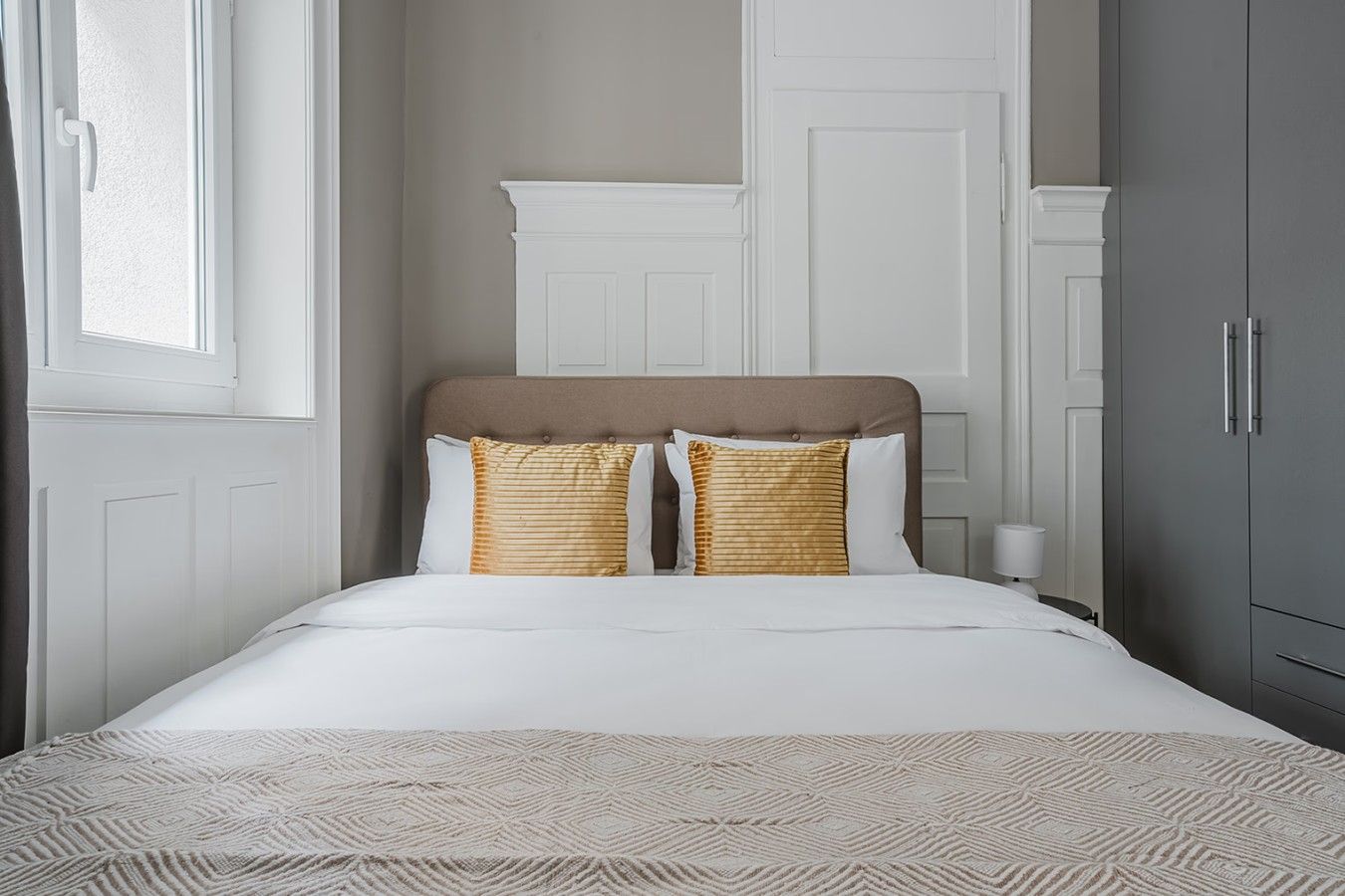 A bed with a headboard, two pillows, and a patterned bedspread.