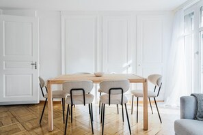 A dining area with a wooden table and six chairs, white walls, and a large window. - Bright 4.5-room apartment in Kreis 6, roof terrace, near ETH (Zürich)