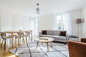 Ein modernes Wohnzimmer mit Sofa, Couchtisch und Essbereich.