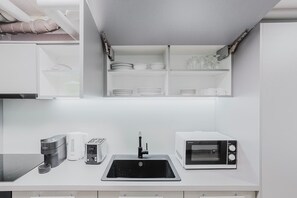 A modern kitchen with a built-in microwave, toaster, and coffee maker. - Bright 1.5-room apartment in Kreis 6, roof terrace, near ETH (Zürich)