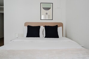 A neatly made bed with a patterned bedspread, a headboard, and two black pillows. - Bright 1.5-room apartment in Kreis 6, roof terrace, near ETH (Zürich)