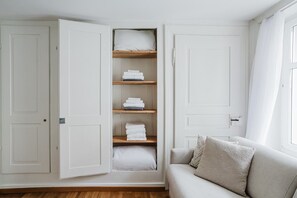 A room with a built-in wardrobe with multiple shelves, a sofa, and a window with curtains. - Bright 4.5-room apartment in Kreis 6, roof terrace, near ETH (Zürich)