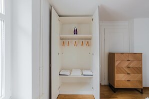 A walk-in closet with open doors, wooden drawers, and hanging clothes racks. - Bright 4.5-room apartment in Kreis 6, roof terrace, near ETH (Zürich)