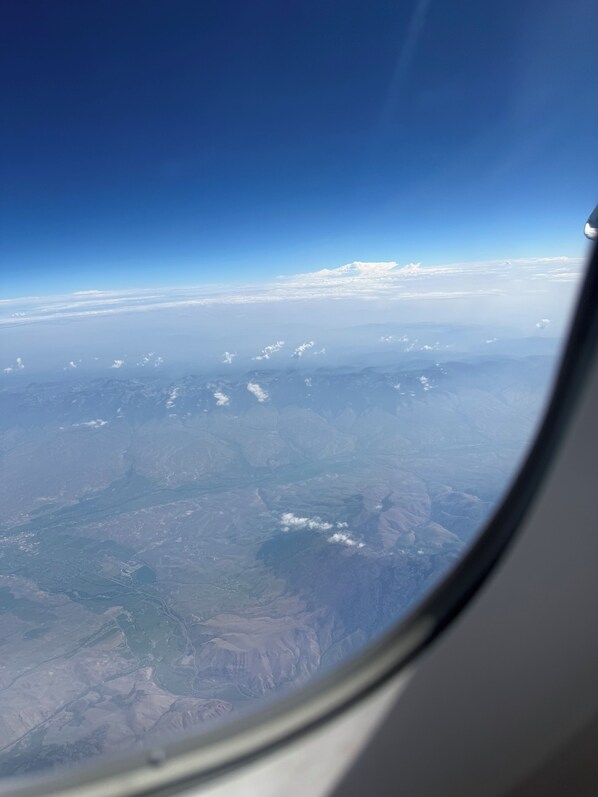 Vista desde la ventana de un avión, con cielo despejado y paisaje distante.