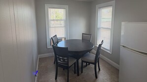 A kitchen with a round table, four chairs, a refrigerator, and two windows with blinds. - 2-bedroom fully updated and new apartment (Elmira)
