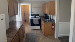 A kitchen with a stove, oven, sink, and wooden cabinets. - 2-bedroom fully updated and new apartment (Elmira)