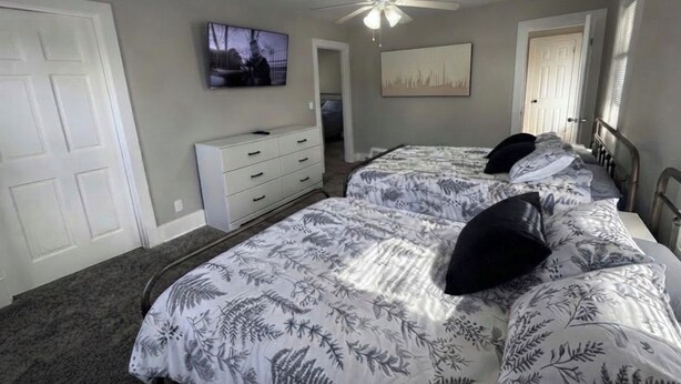A bedroom with two beds, a ceiling fan, a TV on the wall, and a door. - 2-bedroom fully updated and new apartment (Elmira)