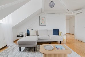 A modern living room with a high ceiling, a sofa, a coffee table, and a framed picture on the wall. - Bright 4.5-room apartment in Kreis 6, roof terrace, near ETH (Zürich)
