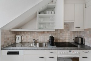 A modern kitchen with a built-in dishwasher, a coffee maker, a toaster, and a microwave. - Bright 4.5-room apartment in Kreis 6, roof terrace, near ETH (Zürich)