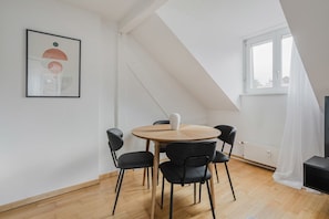A modern room with a round table, four chairs, a white vase, and a framed abstract artwork on the wall. - Bright 4.5-room apartment in Kreis 6, roof terrace, near ETH (Zürich)