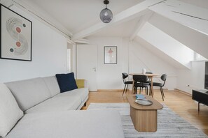 A modern living room with a sofa, a coffee table, and a dining area with chairs. - Bright 4.5-room apartment in Kreis 6, roof terrace, near ETH (Zürich)