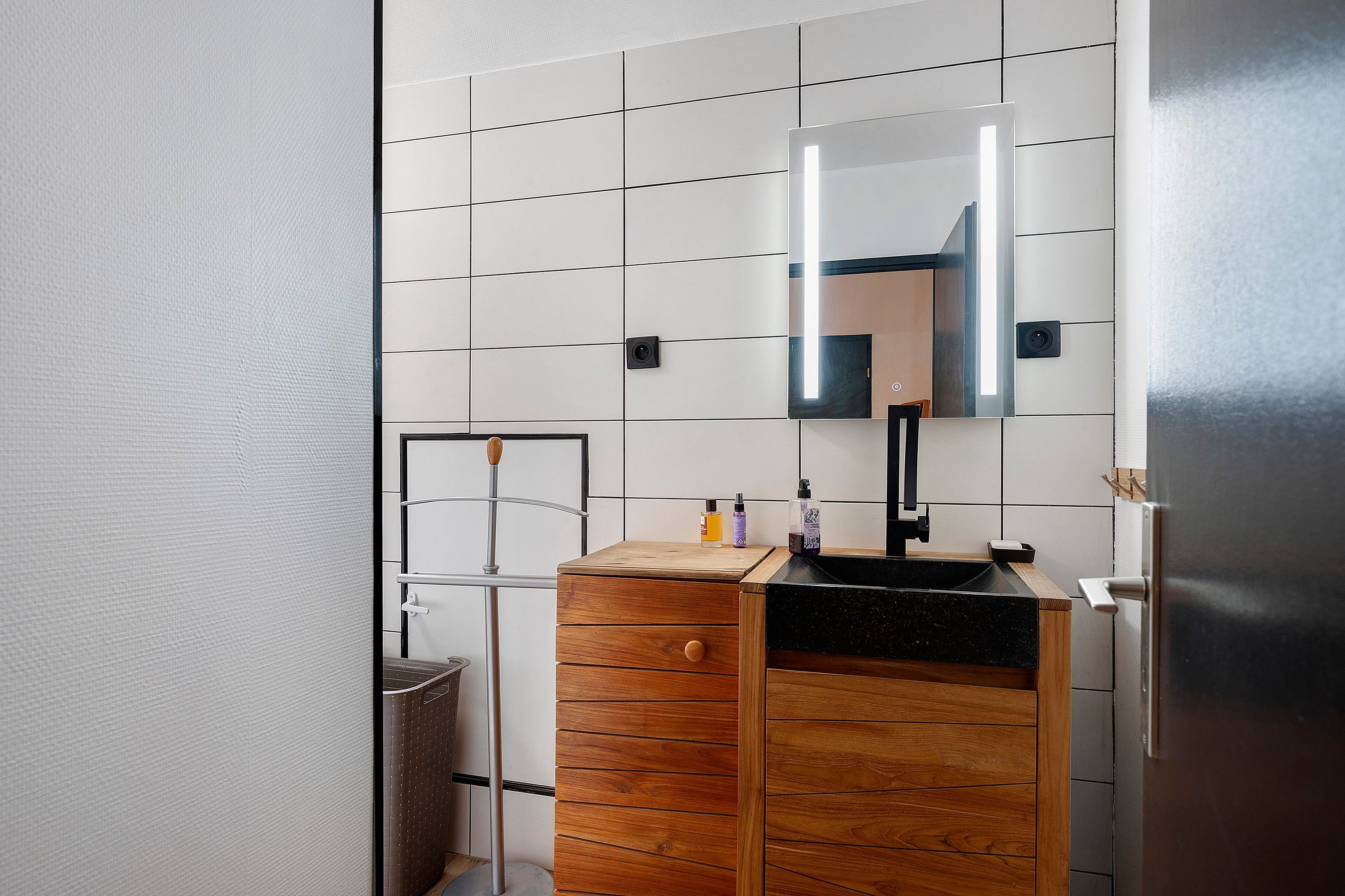 A bathroom with a wooden vanity, a mirror, and a black sink.
