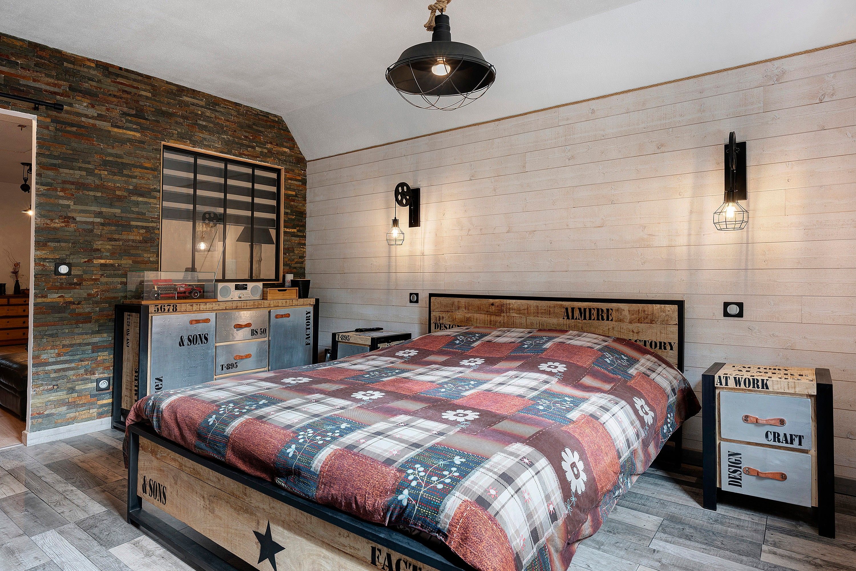A bedroom with a bed, a dresser, a mirror, and a wall with a wooden panel design.