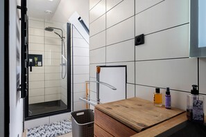 A modern bathroom with a shower, a wooden vanity, and a mirror.