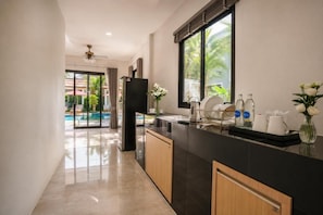Una cucina moderna con un piano di lavoro nero, mobili in legno e vista su una zona piscina all'aperto.
