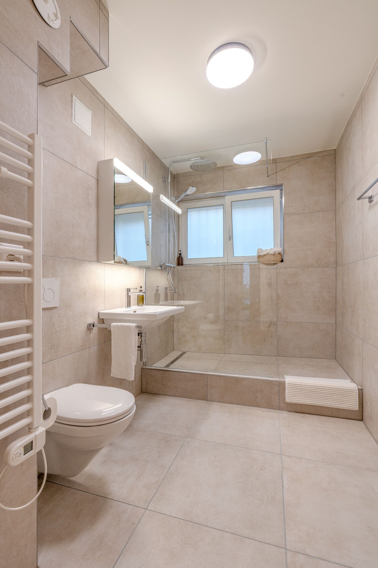 Une salle de bain moderne équipée de toilettes, d’un lavabo et d’un espace douche.