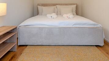Ein Schlafzimmer mit Bett, Kissen, Kopfteil, Nachttisch, Wandleuchte und Teppich.