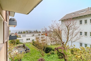 A residential area with a view of the sea, a garden with potted plants, and a building with multiple windows.