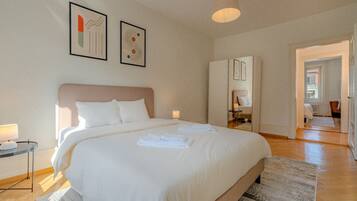 Une chambre d’hôtel avec un grand lit, une table de chevet avec une lampe et des œuvres d’art accrochées au mur.
