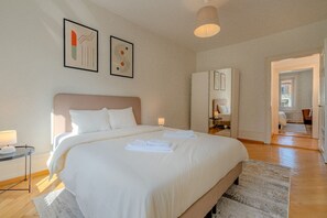 Une chambre d’hôtel avec un grand lit, une table de chevet avec une lampe et des œuvres d’art accrochées au mur.