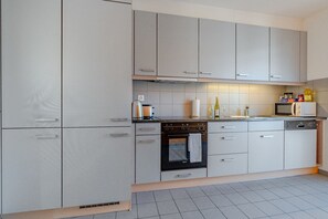 Cozinha moderna com armários cinza, fogão, forno e micro-ondas.