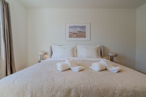 A hotel room with a bed, two bedside tables, a framed picture on the wall, and a window with curtains. - Garden-level 2-BR with parking · Kilchberg (Kilchberg)