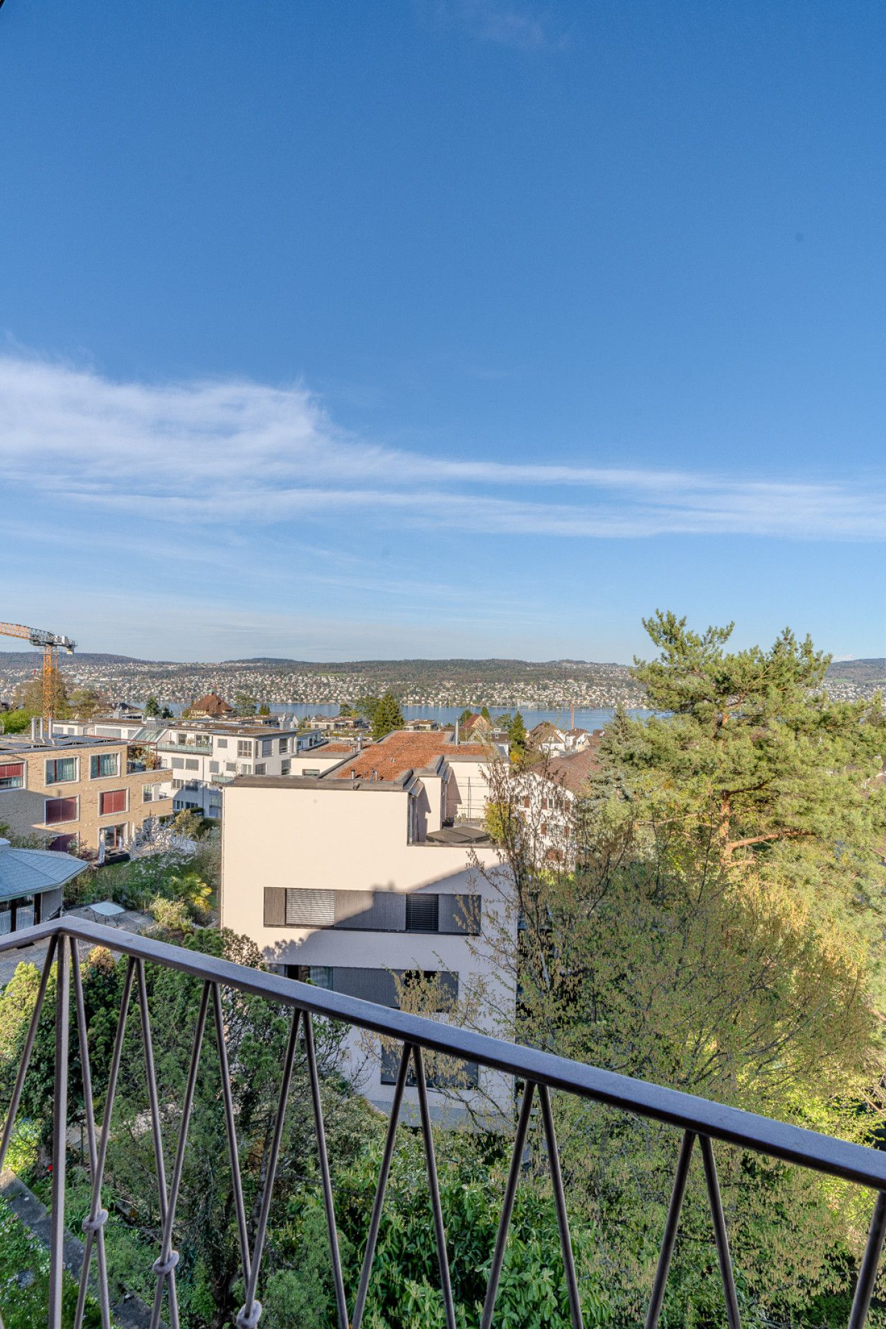 Ein Wohngebiet mit modernen Gebäuden, blauem Himmel und Blick auf eine Stadt in der Ferne.